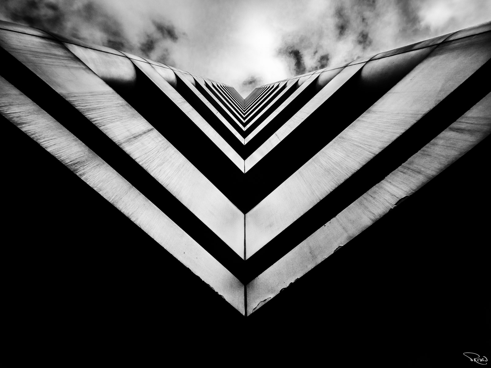 Looking up at a black-and-white skyscraper shaped like a series of deep V angles moving off into the distance.